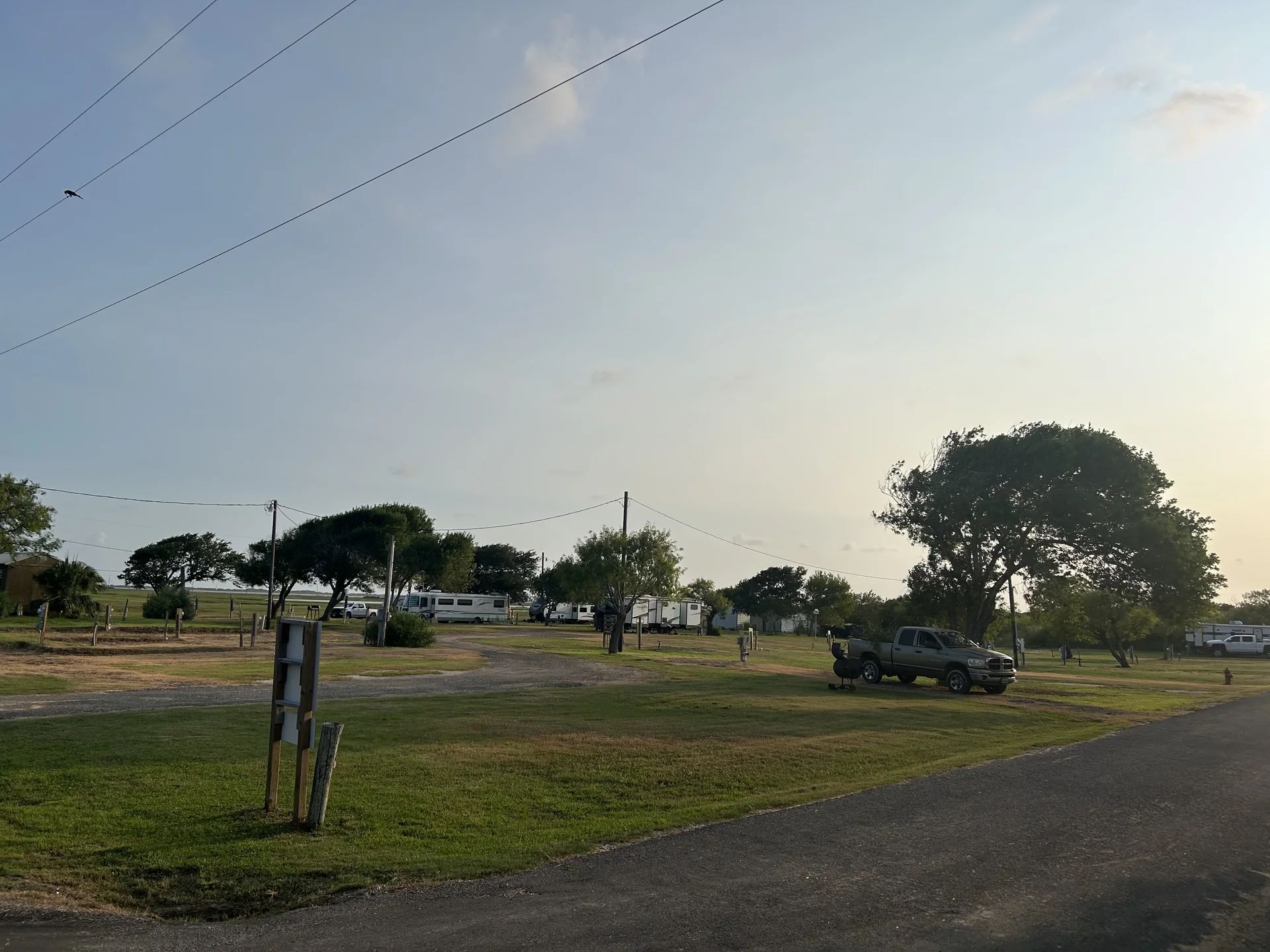 Wide current view of occupied RV sites and open park grounds at Down By The Bay RV Resort