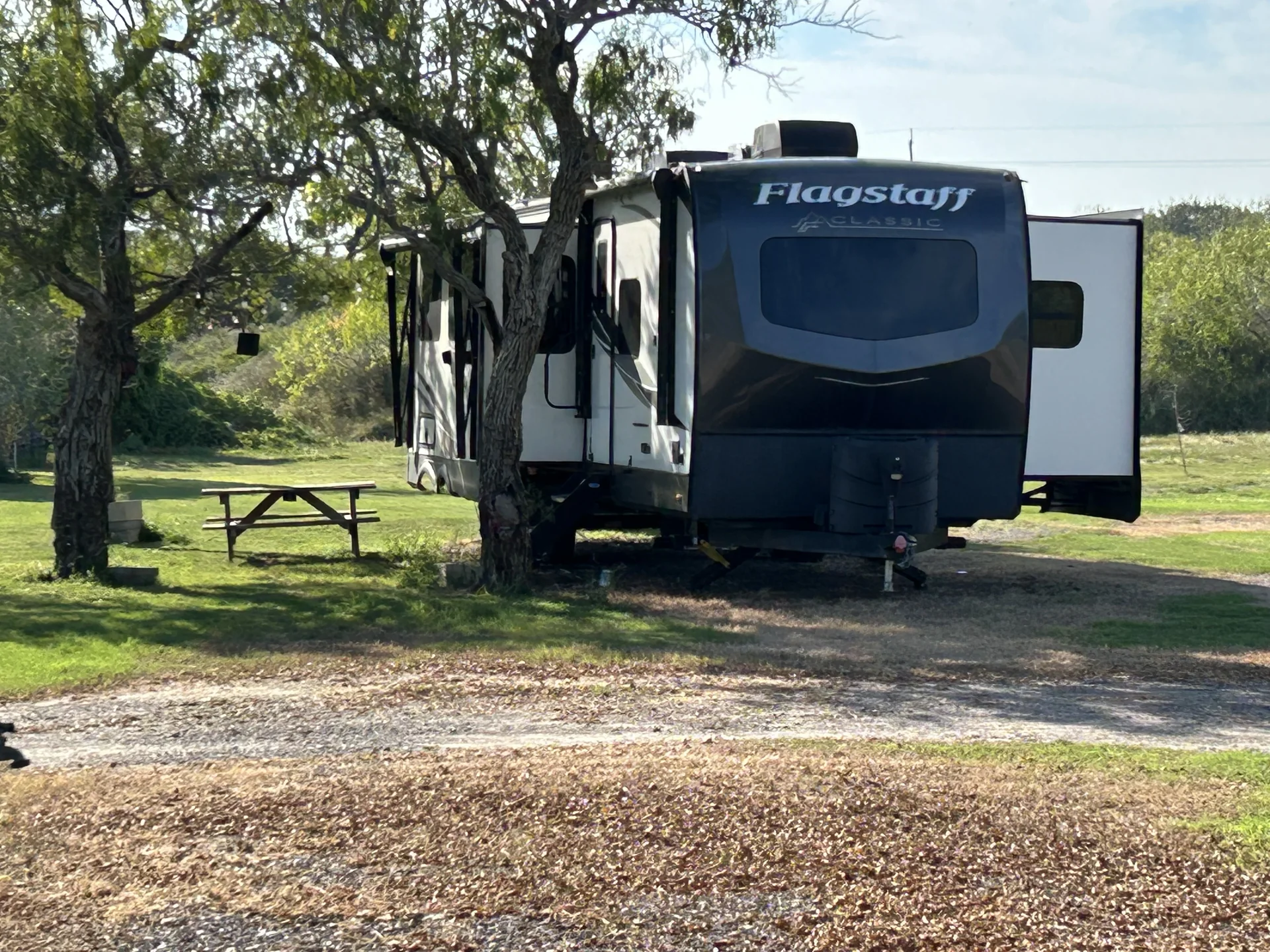 Guest RV beneath mature shade trees at Down By The Bay RV Resort